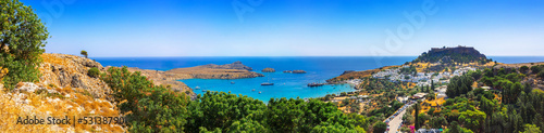Panoramic view of colorful harbor in Lindos village and Acropolis  Rhodes. Aerial view of beautiful landscape  ancient ruins  sea with sailboats and coastline of island of Rhodes in Aegean Sea