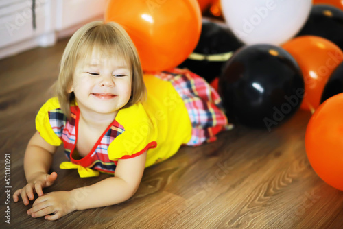 Portrait of a small child lying on the floor in a room decorated with balloons. Happy childhood concept.