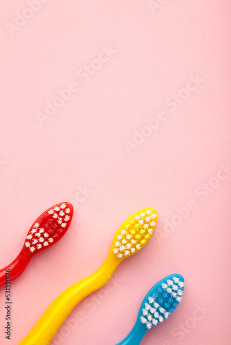 Colorful toothbrushes on pink background. Top view