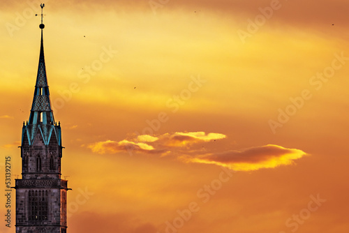 Church tower in Nuremberg in front of orange sunset over the city in Germany.  photo