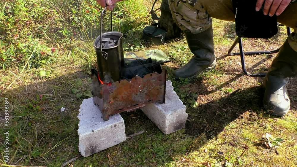The traveler puts a camping pot with water on the fire. The food of nature-traveling hikers. The traveler puts a camping pot with water on the fire. The food of nature-traveling hikers.