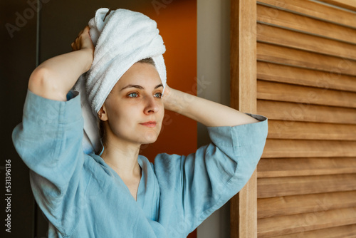 woman in a blue bathrobe after shower and white towel on her head. Morning concept