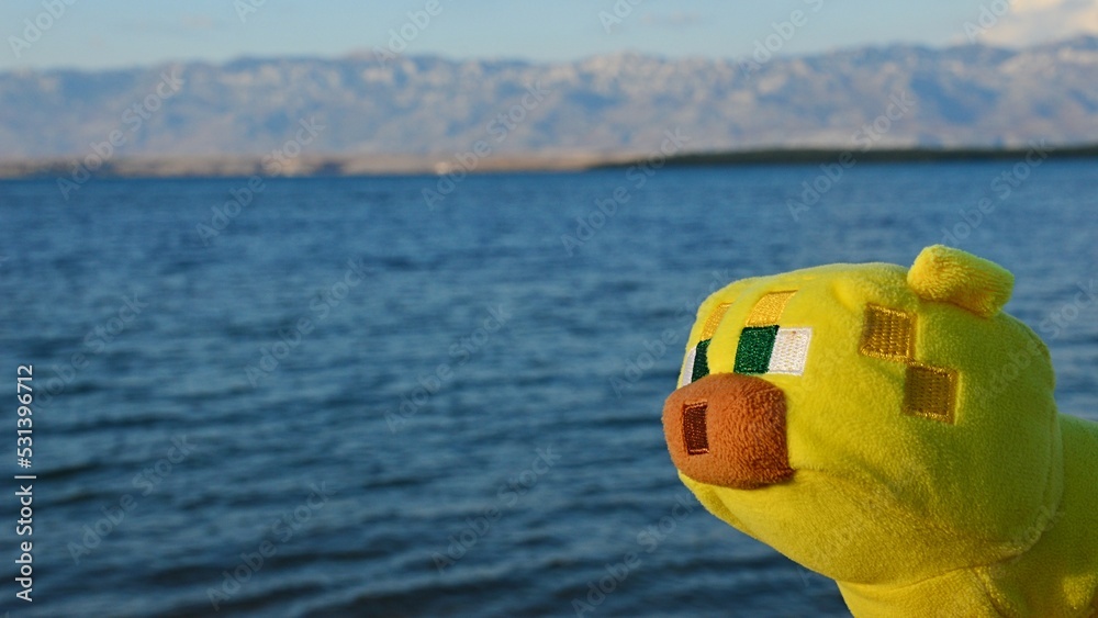 Fototapeta premium Minecraft plush toy of Ocelot cat sunbathing in afternoon sunshine in Nin bay, northern Dalmatia, Croatia.