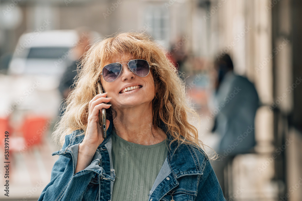 mature woman talking on mobile phone in the street mature woman talking on mobile phone in the street
