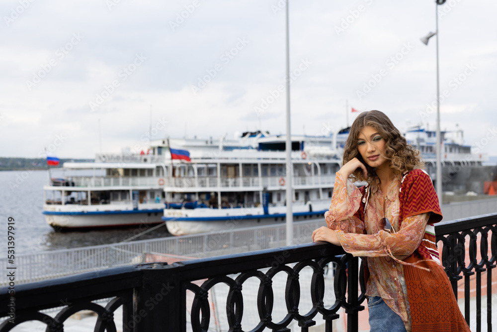 Portrait of a beautiful girl on the background of the embankment of a large river