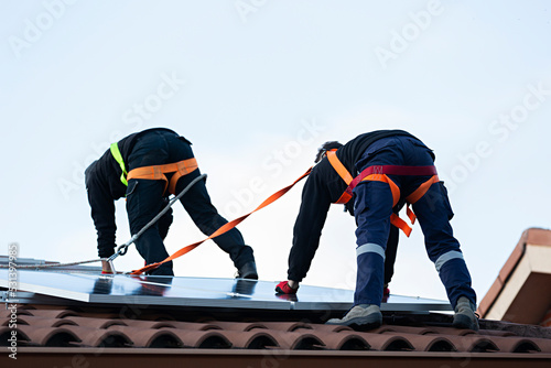 Dos técnicos instalando en el tejado de un chalet placas solares.