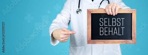 Selbstbehalt Krankenkasse. Arzt zeigt medizinischen Begriff auf einem Schild/einer Tafel photo