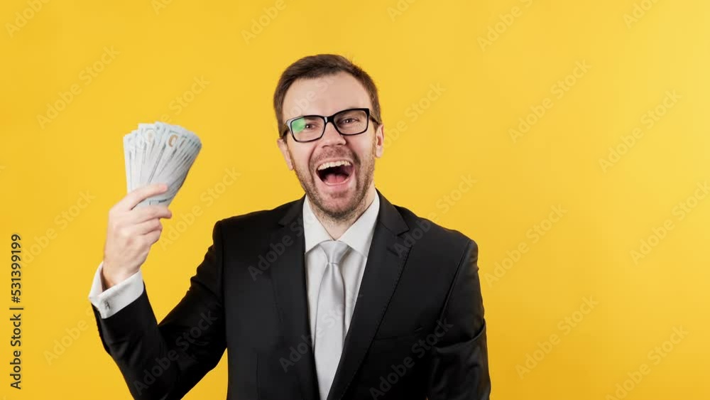 Rich man waving money dollar cash banknotes bills like fan over yellow background. Big income. Businessman celebrating his successful win. 4K, UHD Rich man waving money dollar cash banknotes bills like fan over yellow background. Big income. Businessman celebrating his successful win. 4K, UHD