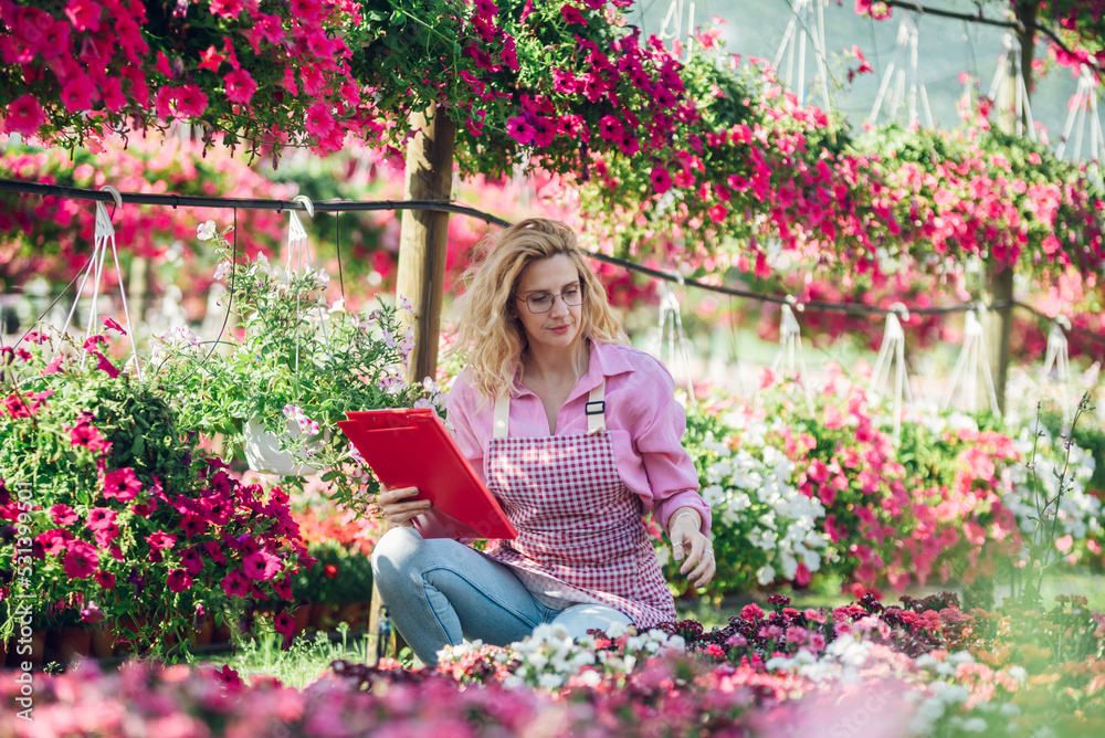 Woman working in a greenhouse flower plant nursery Woman working in a greenhouse flower plant nursery
