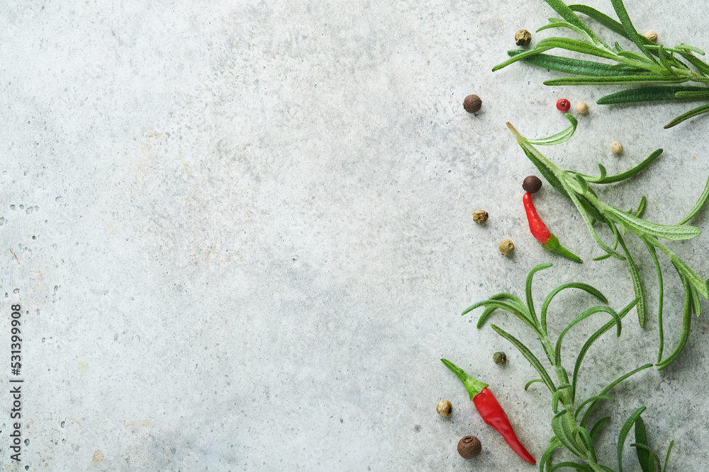 Food cooking background. Green rosemary branches, peppercorns and hot peppers at light grey slate table. Food ingredients top view.
