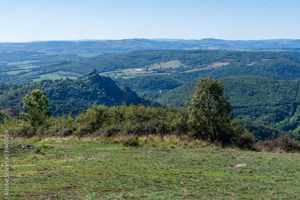 Panorama sur la vallée de l'Allagnon avec ses vallées et son château de léotoing, toutes ses montagnes boiséees sur le chemin de randonnée des chaux dans le puy de dôme