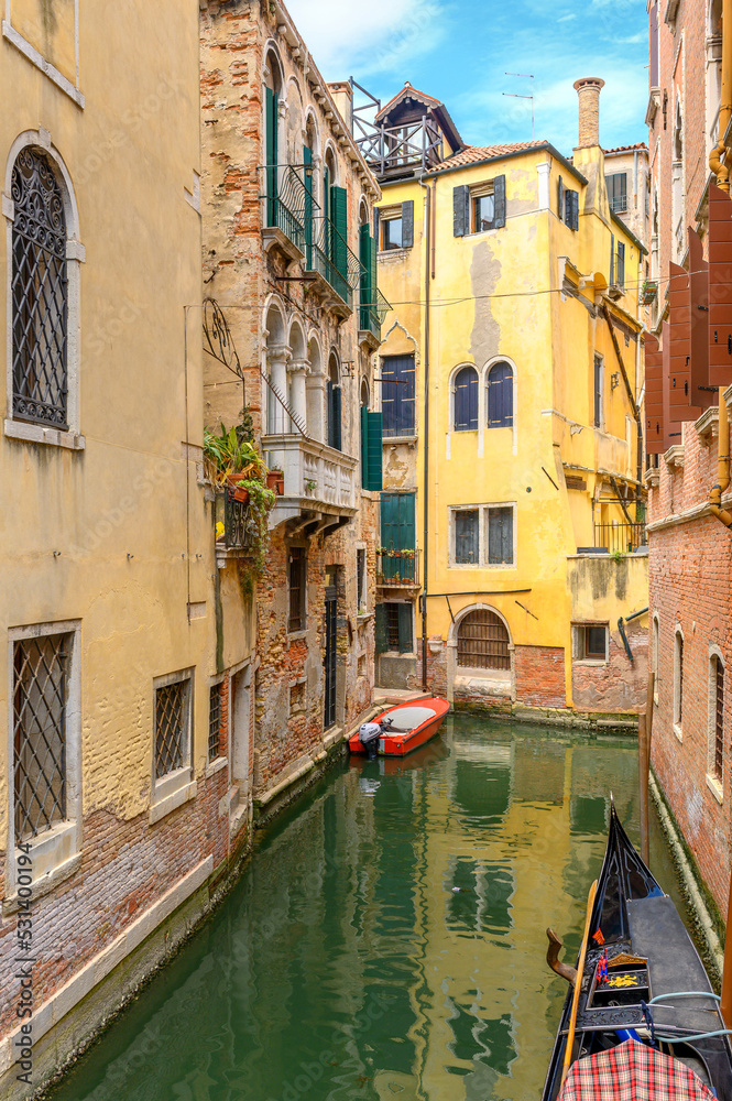 View on the narrow cozy streets of the canals with parked boats in Venice, Italy. Architecture and landmark of Venice.