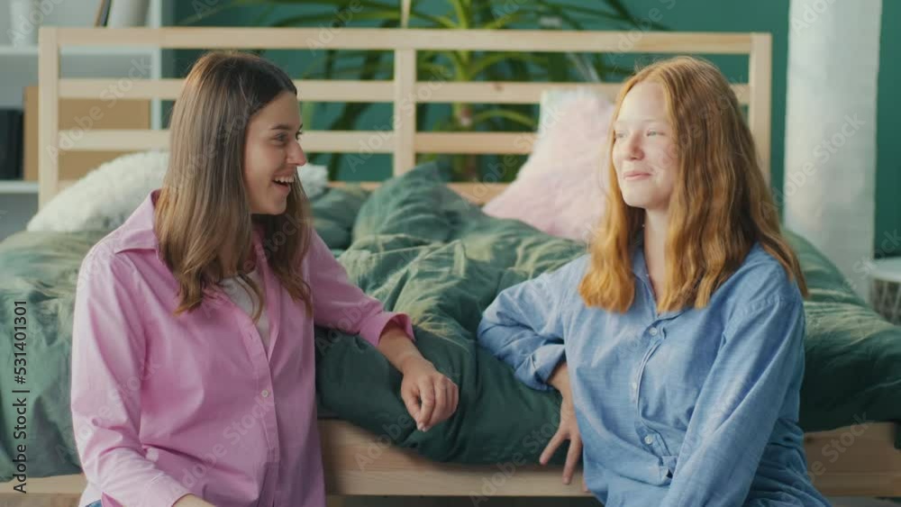 Two Girlfriends, Students at Home Talking, Gossip, Have Fun, Smiling while Sitting on the Floor near Bed. Adolescence Concept, Mental and Emotional Health. Body Positive. Mental Health. Two Girlfriends, Students at Home Talking, Gossip, Have Fun, Smiling while Sitting on the Floor near Bed. Adolescence Concept, Mental and Emotional Health. Body Positive. Mental Health.