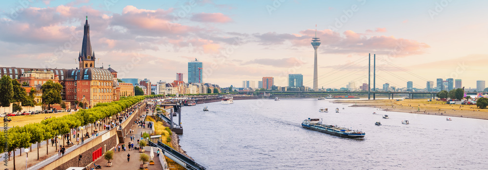 Urban panoramic cityscape view of Dusseldorf old town and transportation waterway of the whole of Germany - the Rhine River, along which large barges and small ships are sailing - obrazy, fototapety, plakaty 