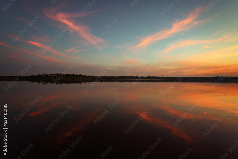 Unique sunset over the lake with a mirror reflection of the clouds