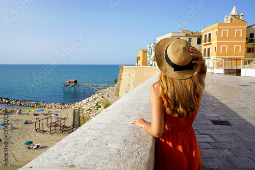 Summer holiday in Italy. Back view of young traveler woman visiting the old town of Termoli, Molise, Italy. photo