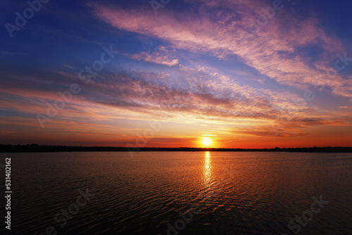 Sunrise over the lake with reflection of clouds and sun © pobaralia