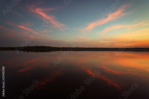 Unique sunset over the lake with a mirror reflection of the clouds