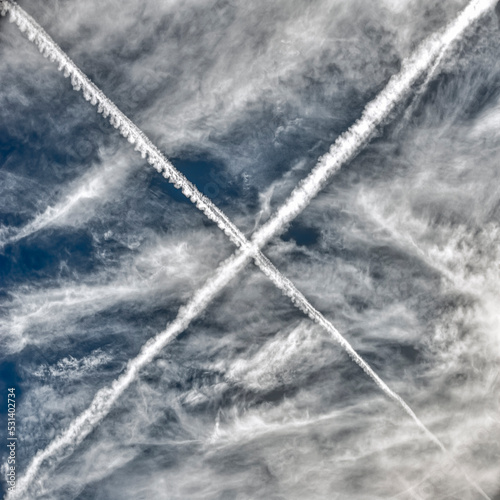 Zwei sich im rechten Winkel am Wolkenhimmel kreuzende Kondensstreifen von Flugzeugen