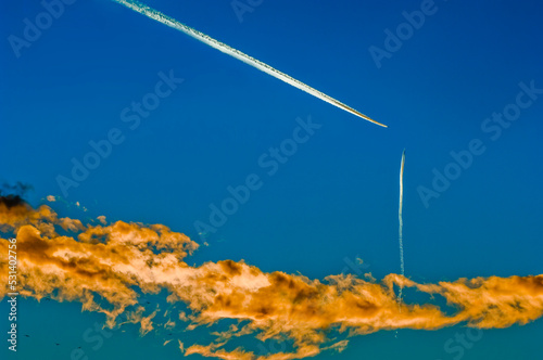 Zwei scheinbar auf Kollissionskurs befindliche Verkehrsflugzeuge am Himmel mit orange beleuchteter Wolke