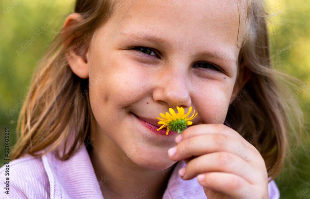 The child smells a flower. Little girl is resting in the park. Copy space. Portrait of a pretty cute girl close-up. The child smells a flower. Little girl is resting in the park. Copy space. Portrait of a pretty cute girl close-up.
