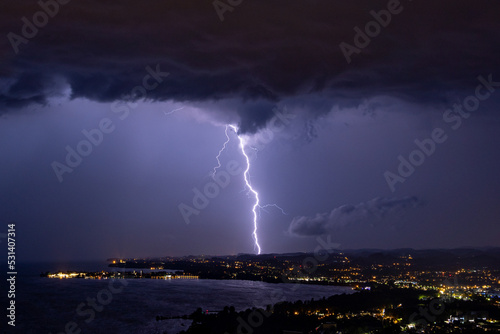 Massive lightning strike during thunderstorm over the Bodensee lake in Austria/Germany with the village Lindau in the foreground