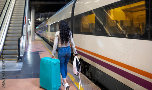 Portrait of a businesswoman traveling on foot through a train station or airport going to boarding gate with carry-on luggage. Concept of female traveler, travel and tourism.