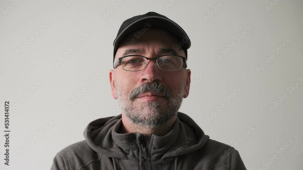 Bearded man in a cap and glasses on a white background in the studio looking at the camera and smiles. Bearded man in a cap and glasses on a white background in the studio looking at the camera and smiles.