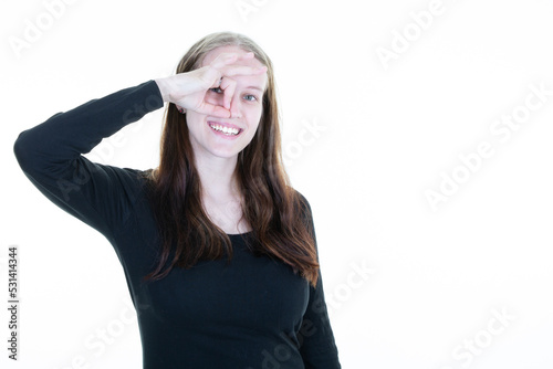 beautiful and young woman blonde standing over isolated white background with happy face smiling doing ok sign with hand on eye looking in fingers