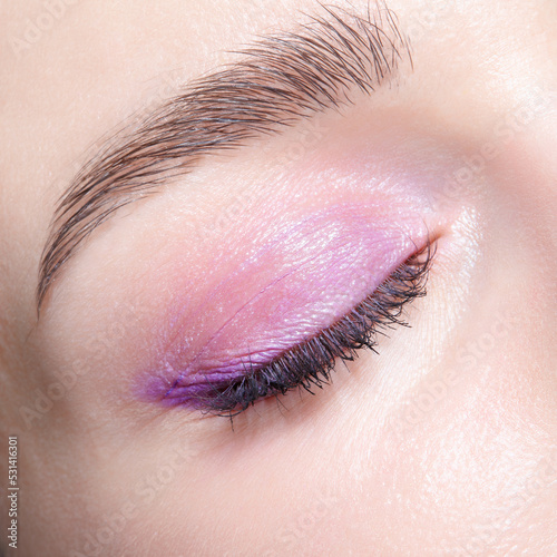 Closeup macro shot of closed human female eye. Woman with perfect skin and pink eyes shadows
