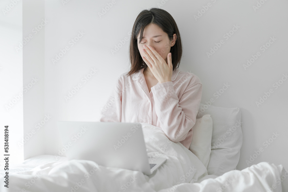 The woman sat on the bed yawning The woman sat on the bed yawning