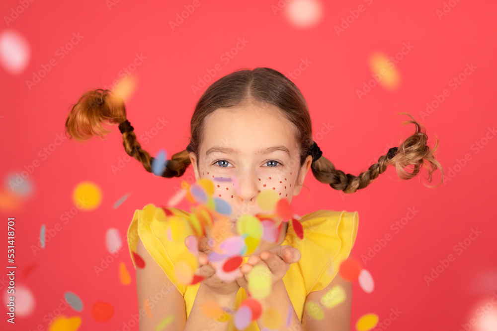 Funny girl playing at home. Child blowing confetti.