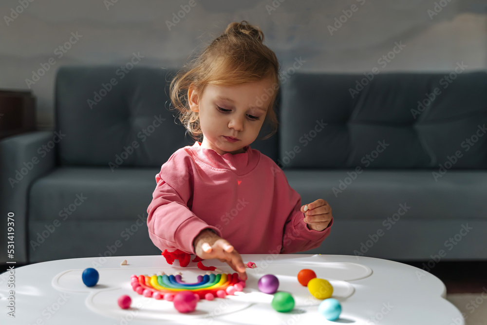 A little girl playing with rainbow from play dough for modeling. Art Activity for Kids. Fine