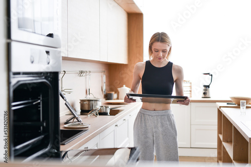 Woman carries tray to put in oven for baking