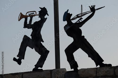 Silhouette metal cutouts of dancing Orthodox Jewish musicians on a rooftop in northern Israel.