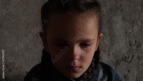 A child wipes tears from his face. A little girl is crying. War in Ukraine. A bomb shelter  photo