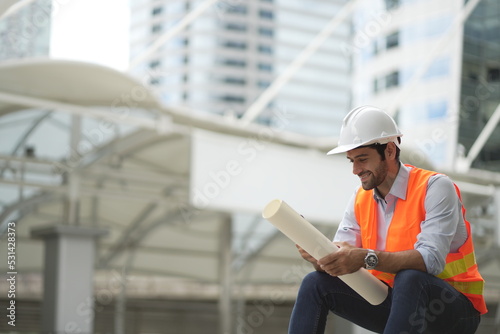 Architect or engineer with blueprints. Cauacsian Engineer checking plan on construction site. modern structure. photo