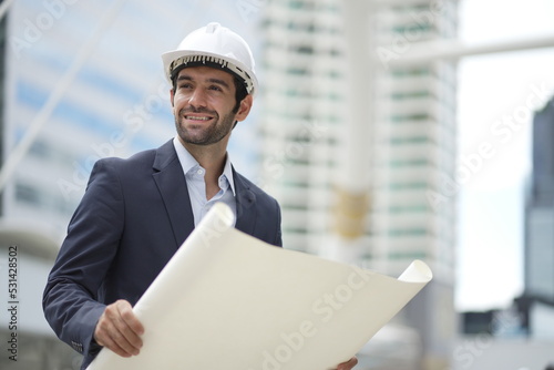 Architect or engineer with blueprints. Cauacsian Engineer checking plan on construction site. modern structure. photo