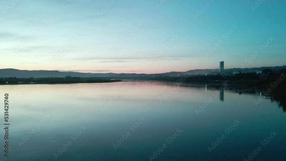 blue tones of view over the river and the riverside of small city, buildings and city lights on the horizon reflected in water blue tones of view over the river and the riverside of small city, buildings and city lights on the horizon reflected in water