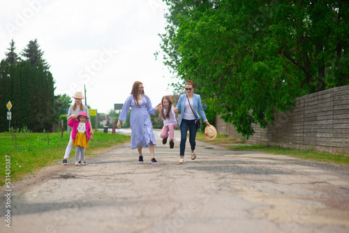 Group of happy family people-two sisters and little girls walking down the city street on a sunny summer day