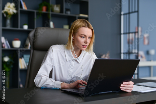 Young woman sitting at home office using laptop