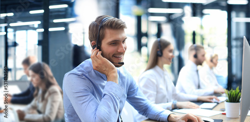 Portrait of call center worker accompanied by his team. Smiling customer support operator at work.