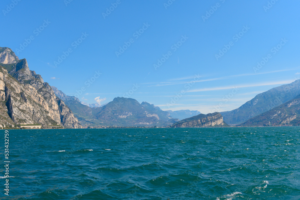 The beautiful Garda lake in Italy, seen from onboard a tourist ferry. It is a beautiful summer day, with just a little bit of clouds.