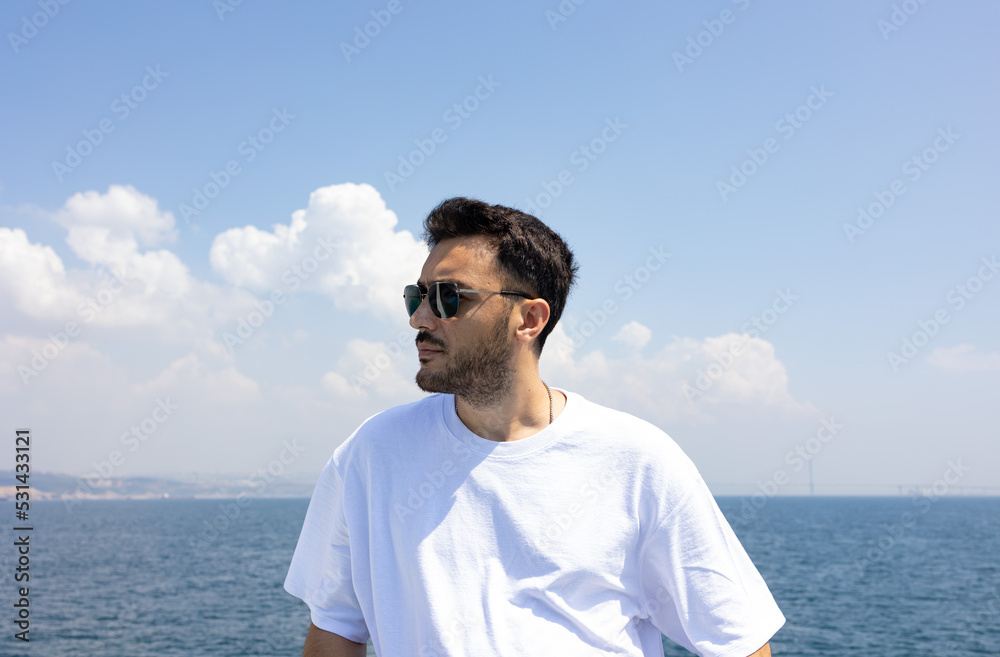 Young, handsome man with sun glasses by sea. Summer vacation, freedom and holiday concept. 