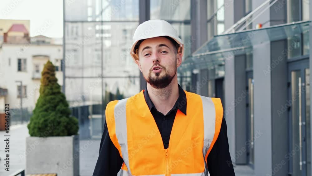 Professional male architect standing near modern glass building office and telling something on camera online or filming vlog. Businessman or architect telling details of project for customer or boss. Professional male architect standing near modern glass building office and telling something on camera online or filming vlog. Businessman or architect telling details of project for customer or boss.