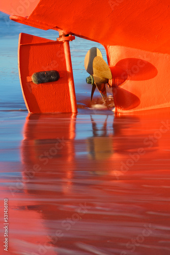 A closeup shot of a orange boat on the beach at sea.