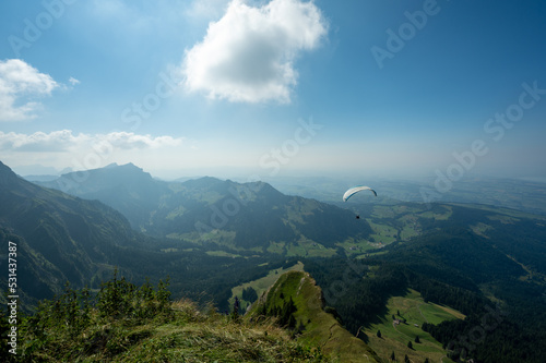 Paraglider flying over the mountains in the late afternoon in Alpnach Switzerland with Lucerne in the background