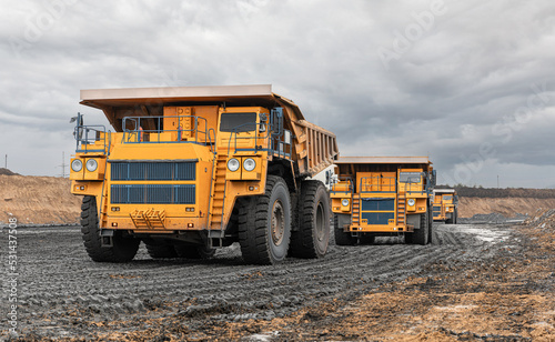 Large quarry dump truck. Big yellow mining truck at work site. Loading coal into body truck. Production useful minerals. Mining truck mining machinery to transport coal from open-pit production