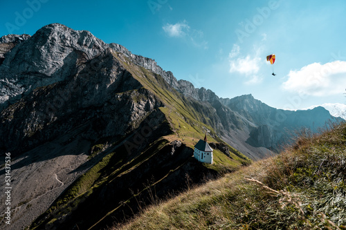View of Mount Pilatus, Klimsenkapelle, and mountain ridge line with a paraglider in the sky Alpnach Switzerland by Lucerne