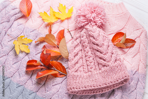 warm knitted hat and sweater, on an autumn wooden white table